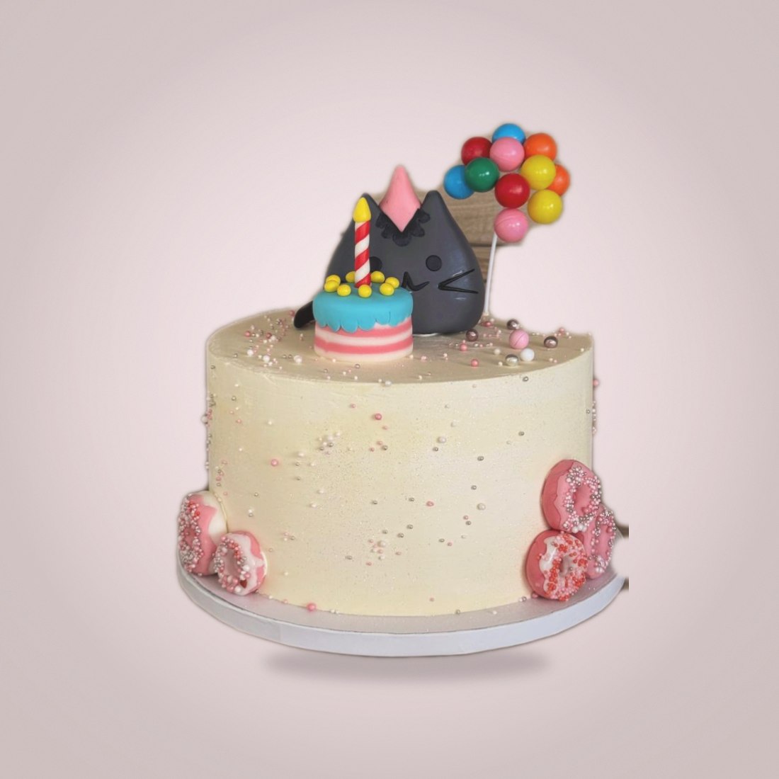 Cream cake with cat topper, donuts and balloons